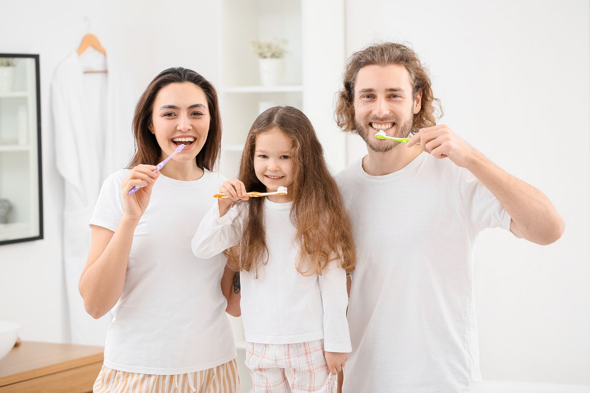 Fun Dental Tools for the Whole Family Family of three brushing teeth together in bright bathroom, promoting dental hygiene and oral care.